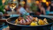© Lesuna - Grilled pork with roasted potatoes in a pan, wine glass in foreground, outdoor setting