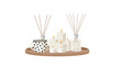 © Mimi - A rustic circular wooden tray features a stylish polka-dot mug accompanied by elegant white candles and two glass reed diffusers for a fragrant home.