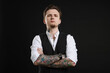 © New Africa - Young man with tattoos in stylish vest and shirt on black background
