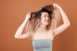 © New Africa - Unhappy woman with tangled hair on brown background