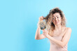 © New Africa - Unhappy woman trying to brush her tangled hair on light blue background, space for text