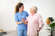 © New Africa - Care worker helping senior woman with walking cane indoors