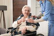 © New Africa - Care worker giving glass of water to senior woman in wheelchair indoors, closeup