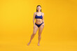 © New Africa - Beautiful woman in stylish swimsuit posing on yellow background