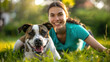 © Anna Huchak - Happy young woman and her pit bull dog lying on the green grass in a park. Pet friendship, summer leisure, outdoor relaxation.