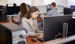 © JackF - Young woman taking notes while working on computer in office space