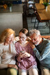 © Geber86 - Grandparents and granddaughter using smartphone on living room sofa