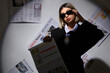 © Pixel-Shot - Beautiful young fashionable businesswoman in stylish sunglasses with newspapers on grey background