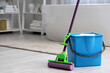 © Pixel-Shot - Mop with blue bucket of water on floor in bathroom