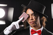 © Pixel-Shot - Young African-American magician with card on black background