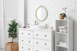 © Pixel-Shot - Chest of drawers with sink, mirror and toothbrushes near white brick wall in bathroom
