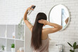 © Pixel-Shot - Beautiful young woman applying hair spray near mirror at home