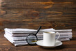 © Pixel-Shot - Morning newspapers, cup of coffee and magnifying glass on wooden background
