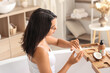 © Pixel-Shot - Beautiful young woman applying coconut oil on her body in bathroom