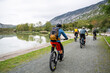 © .shock - Group mountain biking along a lakeside trail with cyclists enjoying outdoor adventure