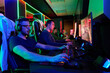 © .shock - Competitive Gamers Playing Multiplayer PC Games In Neon-Lit Esports Gaming Arena With Headsets