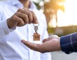 © justark - Close up lifestyle photography of a real estate agent's hand holding a house key with a small wooden house shaped keychain.