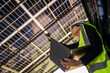 © ultramansk - Engineer in safety vest and helmet pointing towards a solar powered carport, illustrating eco-friendly innovation in parking infrastructure. Solar panels provide shade and sustainable energy.