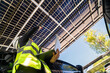 © ultramansk - Engineer in safety vest and helmet pointing towards a solar powered carport, illustrating eco-friendly innovation in parking infrastructure. Solar panels provide shade and sustainable energy.