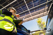© ultramansk - Engineer in safety vest and helmet pointing towards a solar powered carport, illustrating eco-friendly innovation in parking infrastructure. Solar panels provide shade and sustainable energy.