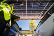 © ultramansk - Engineer in safety vest and helmet pointing towards a solar powered carport, illustrating eco-friendly innovation in parking infrastructure. Solar panels provide shade and sustainable energy.