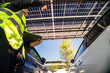 © ultramansk - Engineer in safety vest and helmet pointing towards a solar powered carport, illustrating eco-friendly innovation in parking infrastructure. Solar panels provide shade and sustainable energy.