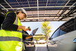 © ultramansk - Engineer in safety vest and helmet pointing towards a solar powered carport, illustrating eco-friendly innovation in parking infrastructure. Solar panels provide shade and sustainable energy.
