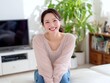 © Jumpei - リビングのソファーでリラックスしながら明るく笑うカジュアルな姿の女性