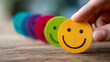 © Kateryna Arkhypova - Hand choosing a happy smiley face paper cutout from options, positive thinking and mental health assessment concept, World Mental Health Day, child wellness, with copy space