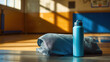 © Chaiwit - Blue water bottle and towel rest on gym bench with sunlight streaming in, perfect for back to school sports and fitness activities