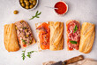 © petrrgoskov - Variety of sandwiches with tuna, salmon y jamon or prosciutto for breakfast on white background, top view, Bruschetta snacks for wine.