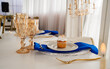© Manuela - Mesa elegante con cupcake decorado, copas doradas y detalles en azul para celebración sofisticada