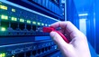 © Hazrat muhammad - It technician plugging a red ethernet cable into a network switch in a data center server room