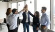 © Kovavic - Diverse business team celebrating success with a high-five in a modern office setting, showcasing teamwork and achievement.