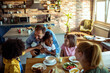 © Davor - Happy family with children laughing at breakfast in cozy home kitchen