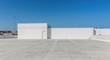 © AkuAku - White building design with clear blue sky and empty concrete car park including copy space