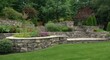 © AImmersive Imagery - Stone wall terraced garden with luxury summer plants and flowers in a beautifully landscaped backyard