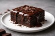 © vxnaghiyev - Delicious chocolate brownie dessert with rich ganache on a white plate and a soft gray background