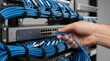© Sara - Hand connecting a blue Ethernet cable to a network switch in a data center rack