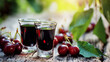 © Bonsales - Cherry liqueur in shot glasses on rustic wooden table, fresh ripe berries with green leaves, summer dessert drink