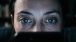 © MR BAT - Close up portrait of a woman's intense focused eyes reflecting the glow of a digital screen in a dimly lit room conveying concentration and digital engagement with subtle signs of fatigue