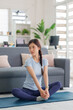 © snowing12 - Asian woman performs yoga stretch meditation home living room fitness workout healthy lifestyle active wellbeing mindful exercise for inner peace self care
