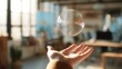© Hot - Close up of hand with floating soap bubble above it in sharp focus, blurred modern office background, bright natural light, soft reflections, high