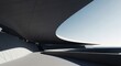 © Nushrat - A sleek, modern architectural structure curves under a clear blue sky with sunlight casting shadows.