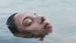 © Robotoyo - Face partially submerged in calm water with reflections and ripples