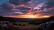 © Thares2020 - Two figures overlook a sprawling vast landscape beneath a dramatic richly colored sunset sky at dusk