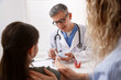 © New Africa - Endocrinologist in glasses checking little girl's blood sugar level with lancet pen while her mother supporting her at white desk in clinic, selective focus
