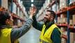 © Vadym - Warehouse workers high five. They are smiling and happy, celebrating success in a modern logistics center. Teamwork and positive vibes are evident between co-workers in industrial setting.
