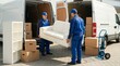 © Ada - Two professional movers in blue uniforms loading a white sofa into a delivery van, furniture transport and home relocation service concept.