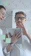 © volha_r - Business professionals collaborate around a glass board, using sticky notes, charts and diagrams to analyze market data, brainstorm strategies and plan projects in a modern office